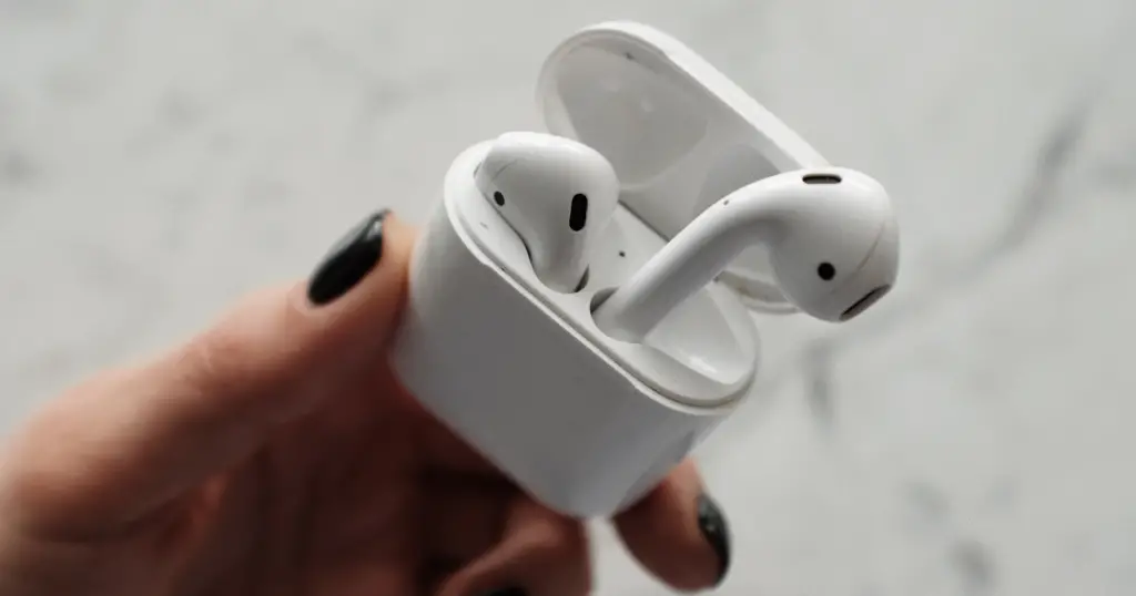 Why Are My AirPods So Quiet - A hand holding AirPods in their case.